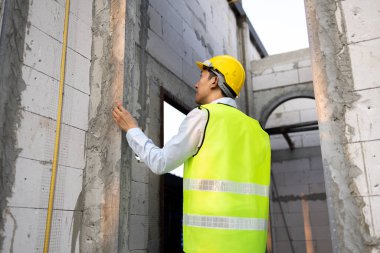 İnşaat alanındaki Asyalı mühendis ev inşaatı için beton materyalleri kontrol ederken. İş yerindeki yapı inşaatında çalışan profesyonel mühendis..
