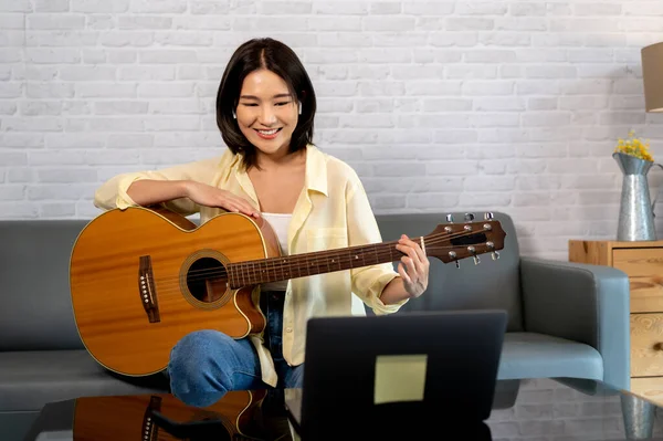 若いアジアの女性は ノートパソコンのコンピュータモニターでギターを練習し 女性ギタリスト オンラインチュートリアル — ストック写真