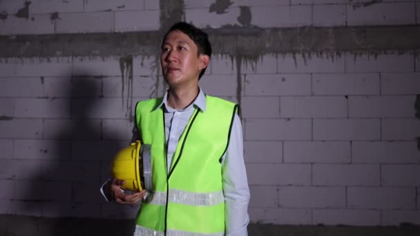 夜間建設現場で疲れやあくびを感じる安全ヘルメット感を持つアジアのエンジニアリングマン 深夜労働の概念 — ストック動画
