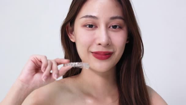 Sorridente Donna Asiatica Che Tiene Fermo Ortodontico Trasparente Sullo Sfondo — Video Stock