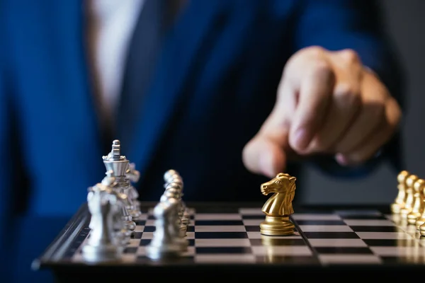 灰色の背景に対してチェスをプレイしながら 黄金の王を保持スーツで認識される男性 — ストック写真