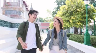 Asyalı romantik çift balayı gezisi için Bangkok 'a gidiyor. Yeni evli erkek ve kadın turist. Tapınakta yürürken el ele tutuşup eğleniyorlar.