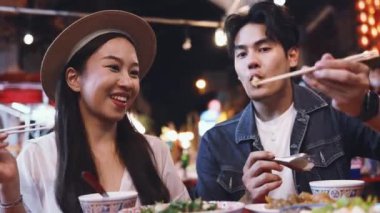Tayland, Bangkok 'ta Çin' de gece marketinde birlikte Tayland sokak yemeği yiyen genç Asyalı çift turistleri.