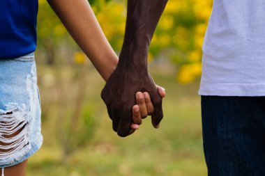 Warm Sunny Day in the Park: Extreme Close-Up Shot of African American Father Holding Hand with Child clipart