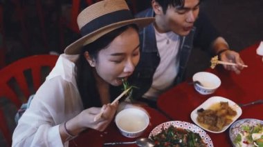 Tayland, Bangkok 'ta Çin' de gece marketinde birlikte Tayland sokak yemeği yiyen genç Asyalı çift turistleri.