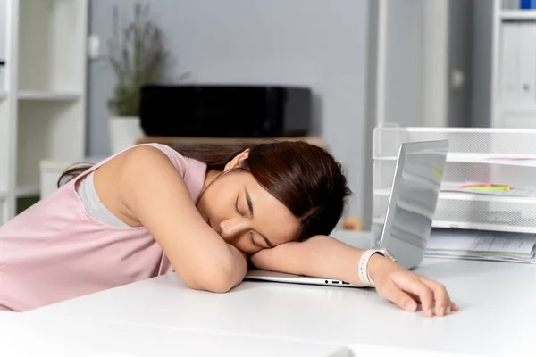 年轻的亚洲女商人睡在她的桌子上 办公室里的背景是一台电脑对讲机 工作狂 困倦的女商人概念 — 图库照片