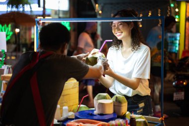 Asyalı, yalnız ve mutlu hipster gezginin portresi Bangkok, Tayland 'da mutlu bir gülümsemeyle hindistan cevizi içeceği alıyor. Güneydoğu Asya 'yı keşfeden kadın turist.