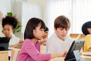 Uluslararası Öğrenciler Tablet Üzerine İşbirliği Yapıyor: Çeşitli İlköğretim Sınıfı Sahnesi Sayısal Öğrenim ve Çok Kültürlü Eğitim Eylemlerini Gösteriyor