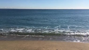 Güneşli bir günde sakin kumlu deniz dalgaları