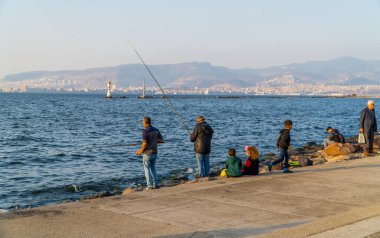 İzmir, Türkiye - 7 Kasım 2022 - İzmir Körfezi kıyısında balık tutan balıkçıların gizli fotoğrafları