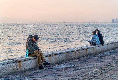İzmir, Türkiye - 7 Kasım 2022 - İzmir Körfezi kıyısında oturan insanlar