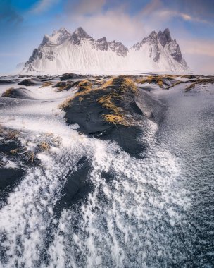 İzlanda 'daki ünlü Vestrahorn Dağı' nın inanılmaz manzarası. Siyah kumsal, güzel bulutlar ve kumul oluşumları.