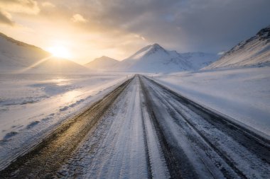 Günbatımında İzlanda 'nın güneyinde düz bir yol, kışın, dağları görünen ve bulutlu bir yol, İzlanda' da 1.