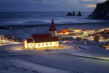 Güney İzlanda 'nın Vik kasabasındaki Reyniskirkja kilisesi, güzel İzlanda kilisesi kışın karanlık çöktükten sonra güzel bir manzara ve arka planda Reynsdrangar' ın deniz yığınları.
