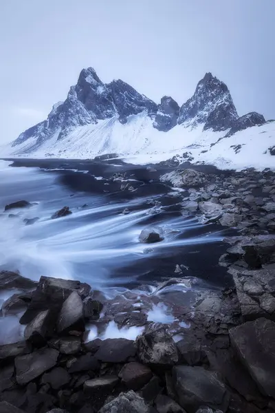 stock image Vertical shot Eystrahorn mountain in Iceland on a gloomy dark evening during winter, waves on the black beach, volcanic landscape