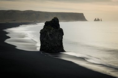 Arnardrangur kaya oluşumu Dyrholaey 'de, Reynisdrangar arka planda, İzlanda' da, İzlanda 'nın güney kıyısında bilinen bir kent simgesidir.