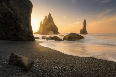 Reynisfjara siyah kumlu plajı, İzlanda 'da, Vik kasabası yakınlarında, güneşin doğuşunda, güzel bazalt kaya oluşumu