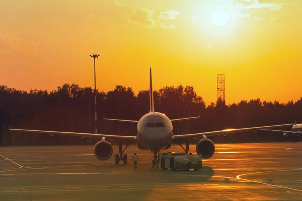 Civil airrcraft push back at sunset. Maintenance of aircraft before the flight
