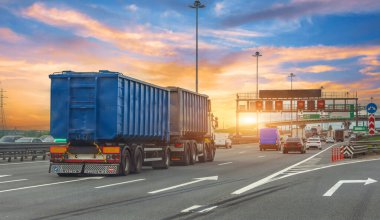 Ayrı römorklu kamyon taşımacılığı diğer arabalar arasında mavi renkli sürücüler. Gün batımında şehir otoyolu boyunca yoğun trafik. Gökyüzü güzel ışık ve bulutlarla dolu.