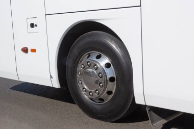 Beyaz bir otobüsün tekeri, parlak bir diskle yaklaşıyor.