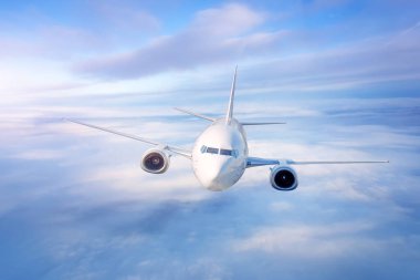 Gökyüzündeki bulutların üstündeki uçak gün doğumunda, alacakaranlık uçuşunda