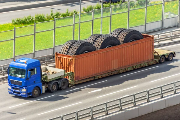 Transportation of huge dump truck wheels in a container on a trailer.