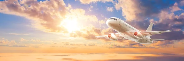 Wide broad panoramic banner of a flying passenger civil jet on a picturesque sunset dawn sky, travel trip