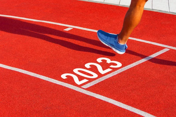 跑步者驾驶一辆红色跑步机越过终点线 车牌号为2023 新年入职概念 — 图库照片