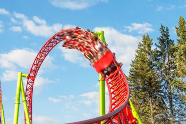 Eğlence arabası dairesel döngüleri baş aşağı eder ve hareket bulanıklığı efektiyle döngünün dışına doğru keskin bir dönüş yapar.