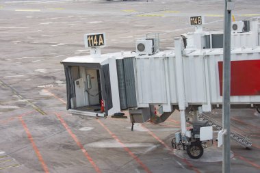 Havaalanı terminalinde telgraf ve uzakta duran bir uçak.