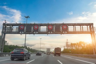 Yoğun kamyon ve araba akıntısı sabah 110 km hız göstergesi olan bir otoyolda gün doğumunda