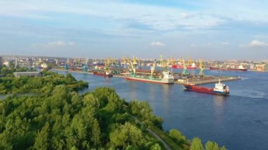 Büyük bir şehrin kargo limanından, yeşil bitki ağaçlarının üzerinden uçarak.