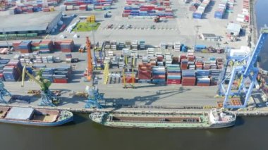 Aerial top view huge cargo ships, moored at the pier in the port, loading goods, metal in aluminum rolls, concrete and other solid raw materials and other useful goods