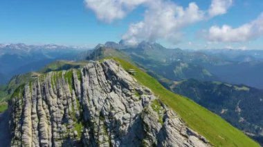 Mountain range alpine meadows on southern slope with clouds in the sky on a sunny day, gorges and peaks extending into the distance of the horizon. Aerial top view