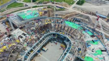 Building site of the arena stadium, a lot of construction equipment at work aerial top view