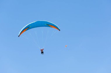 Two paraglider tandem fly against the blue sky, tandem paragliding on distance guided by a pilot