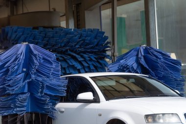 Automatic wash blue brush in action, white car comes out ready clean clipart