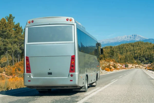 银色闪亮的灰色现代舒适的旅游巴士在阳光明媚的高山上行驶在高速公路上 旅游和长途汽车旅游概念 旅行和乘车旅行 — 图库照片