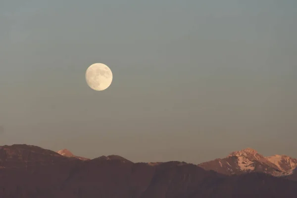 stock image Full moon rises over mountain range evening sky