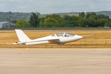 Ultralight planör uçağı çimlerin üzerinde duruyor, Dünya havalimanına iniyor.