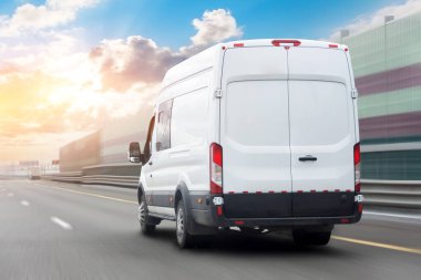 Beyaz minibüs gün batımından önce güzel gökyüzü olan otoyol boyunca hareket bulanıklığı çekiyor. Mal ve paketlerin hızlı teslimat hizmeti