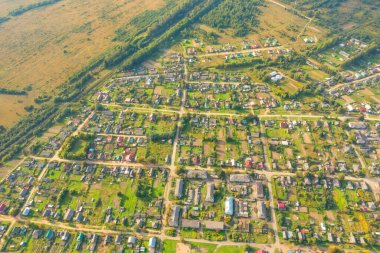 Yukarıdan köy manzarası, ovadaki yeşil tarlalar arasında özel kır evlerinin havadan görünüşü