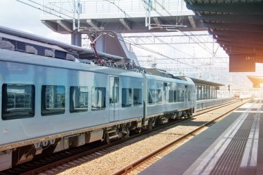 Banliyö elektrikli treni istasyondaki yolcu platformunda kalkışa hazır.