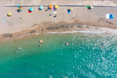 Okyanus kıyısında yüzen turist sayısının az olduğu vahşi sahil, hava manzarası.