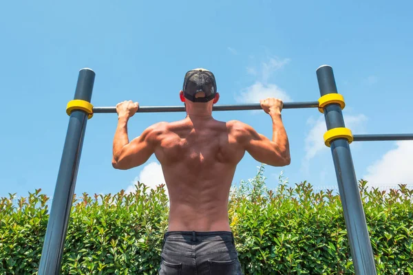 Hombre Musculoso Una Gorra Haciendo Flexiones Barra Horizontal Parque Aire —  Fotos de Stock