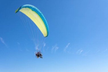 Paragliding, insanlar güneşli bir günde okyanus kıyısındaki plajdan havalanır.