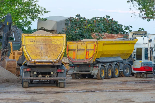 Trucks huge dump trailer heavy bulk cargo parked in a parking lot near a construction quarry