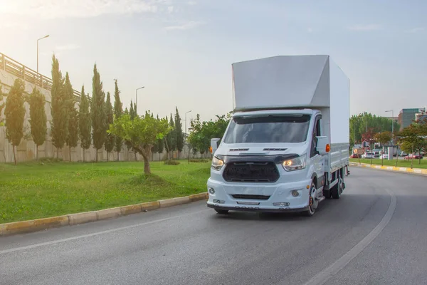 Modern delivery small shipment cargo courier frobt view van moving fast on motorway road turn city urban suburb. Busines distribution and logistics express service