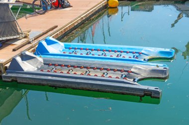 Jet ski kaldırmak, fırlatmak ve depolamak için tekerlekleri olan plastik yüzen panton mini rıhtımı. Rıhtımda suya inmek için korkuluklar var. Körfezde yeşil su