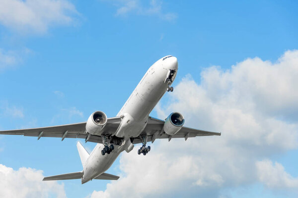 Самолет взлетает, убирая шасси на фоне голубого неба